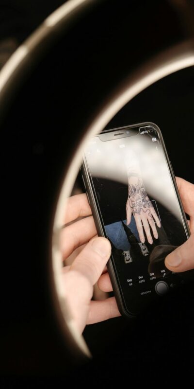 Capturing a detailed view of a tattoo through a smartphone, illuminated by a ring light.