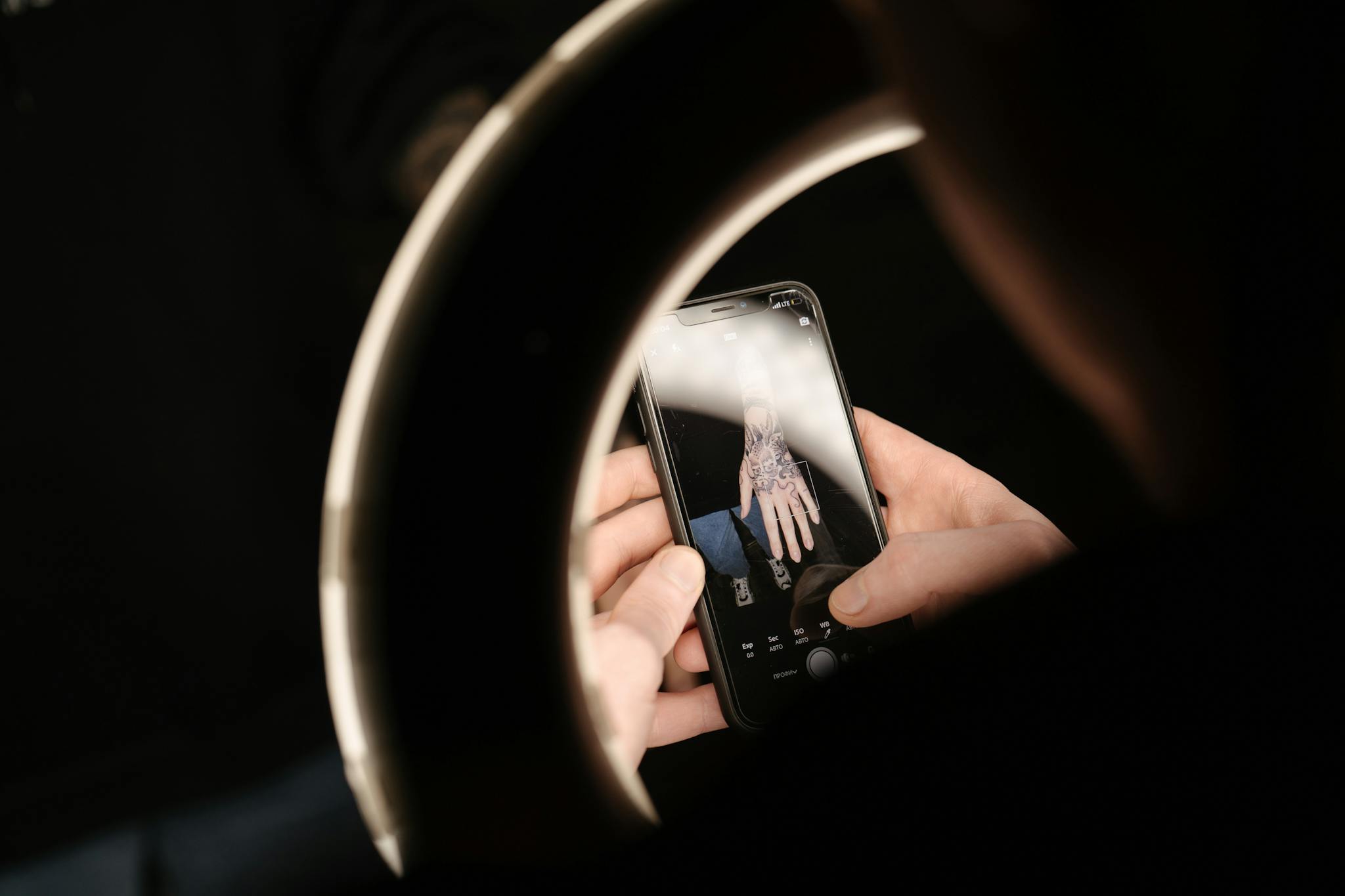 Capturing a detailed view of a tattoo through a smartphone, illuminated by a ring light.